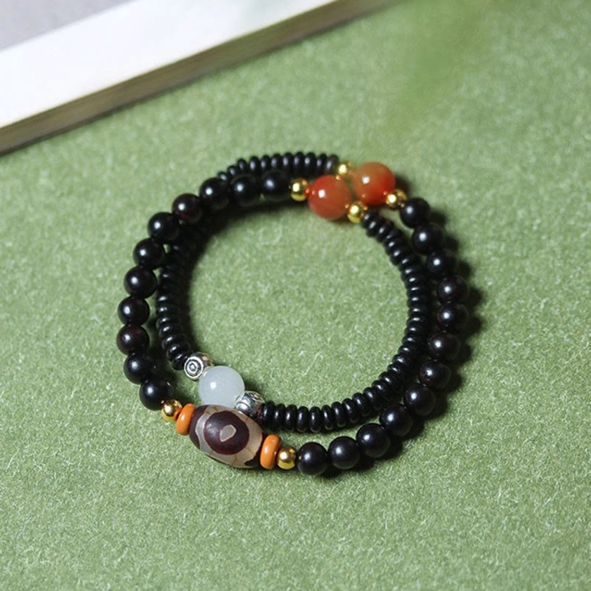 Overhead flat view of ebony and green sandalwood Buddhist bracelet showing full circular double-wrap design with all bead details