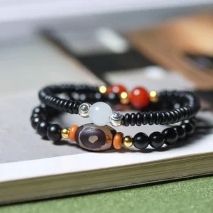 Ebony and green sandalwood dzi bead double wrap bracelet overhead view showing black wood beads with hand-painted dzi bead and red agate accents