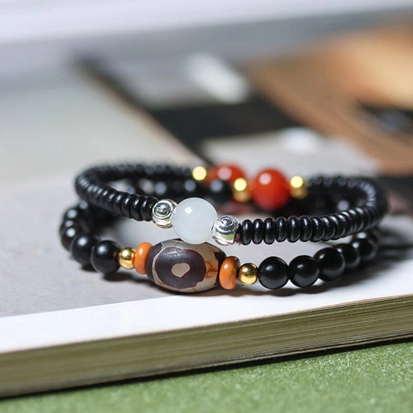 Ebony and green sandalwood dzi bead double wrap bracelet overhead view showing black wood beads with hand-painted dzi bead and red agate accents