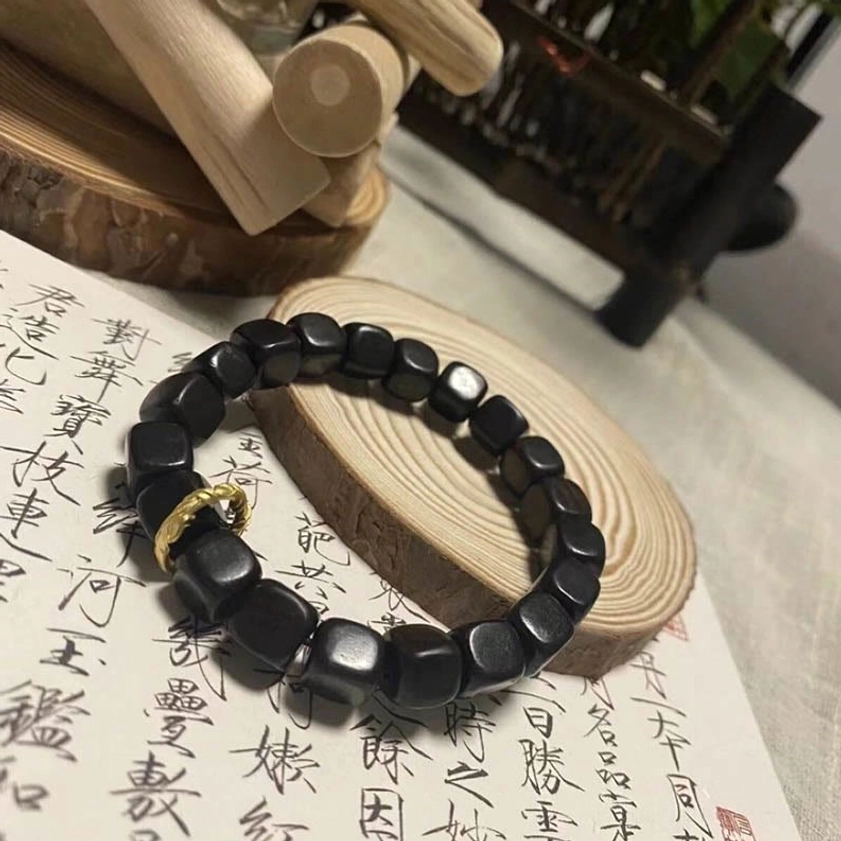 Black square ebony wood beads with twisted gold clasp on Chinese calligraphy paper with wooden ornaments