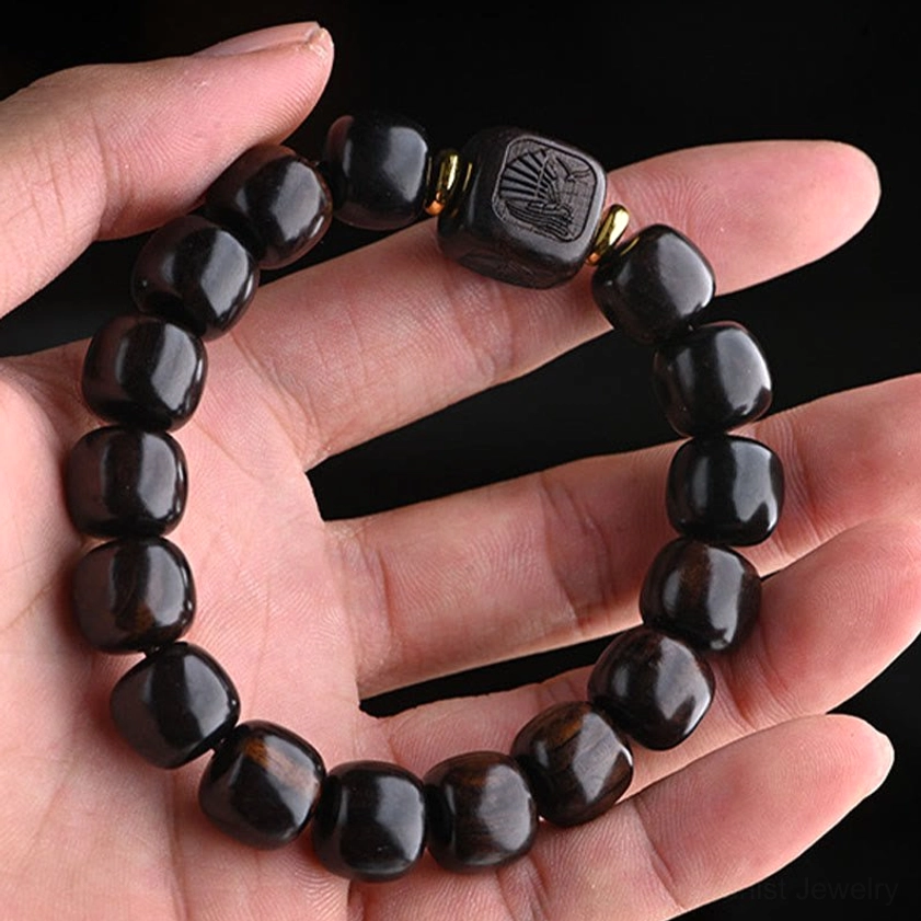 Ebony wood bracelet worn on human palm showing carved square bead and natural wrist size for scale