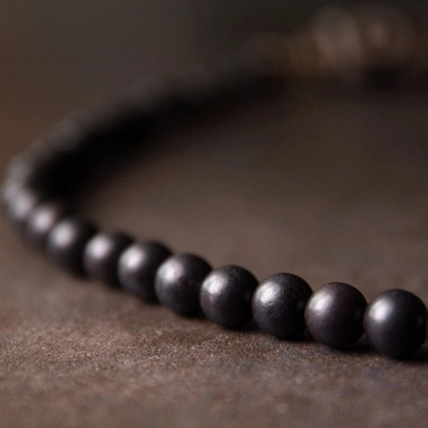 Close-up side angle view of continuous polished dark ebony wood bead strand
