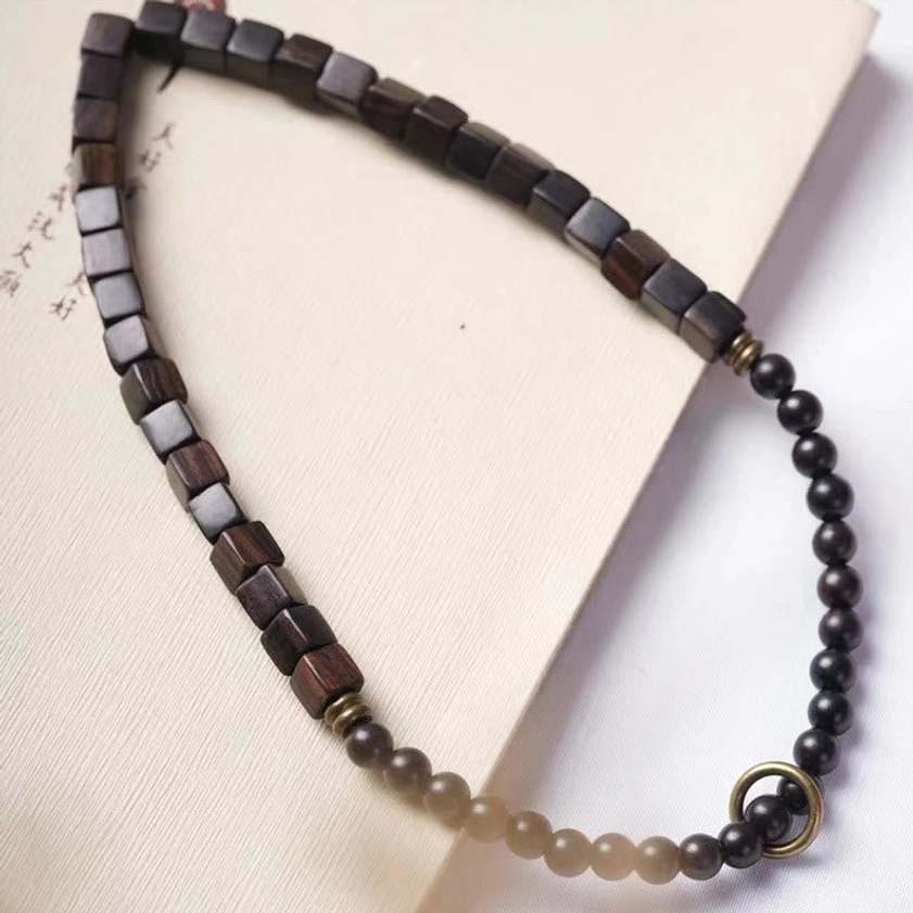 Ebony wood Buddhist bracelet flat lay top-down view with double wrap design displayed on natural paper texture