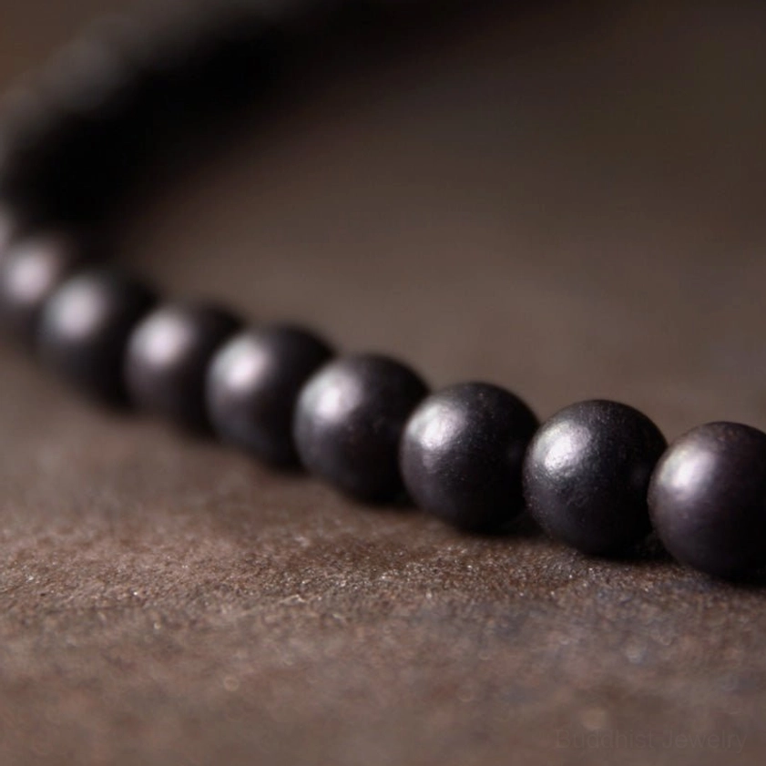 Close-up side angle of polished round ebony wood beads showing smooth dark wood texture