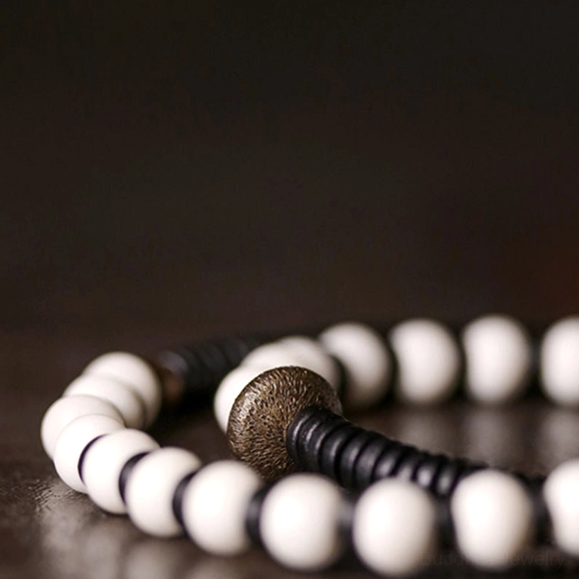 Textured macro detail of irregular ebony wood charm and matte bone beads