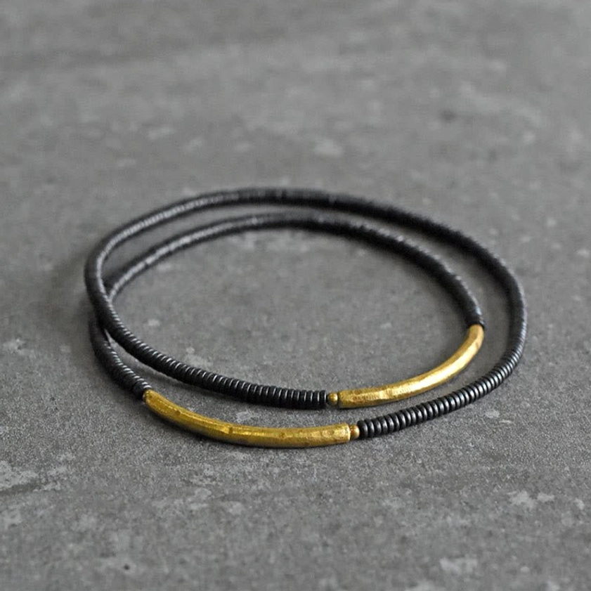 Overhead view of black ebony wood beaded bracelet featuring two curved brass accent details