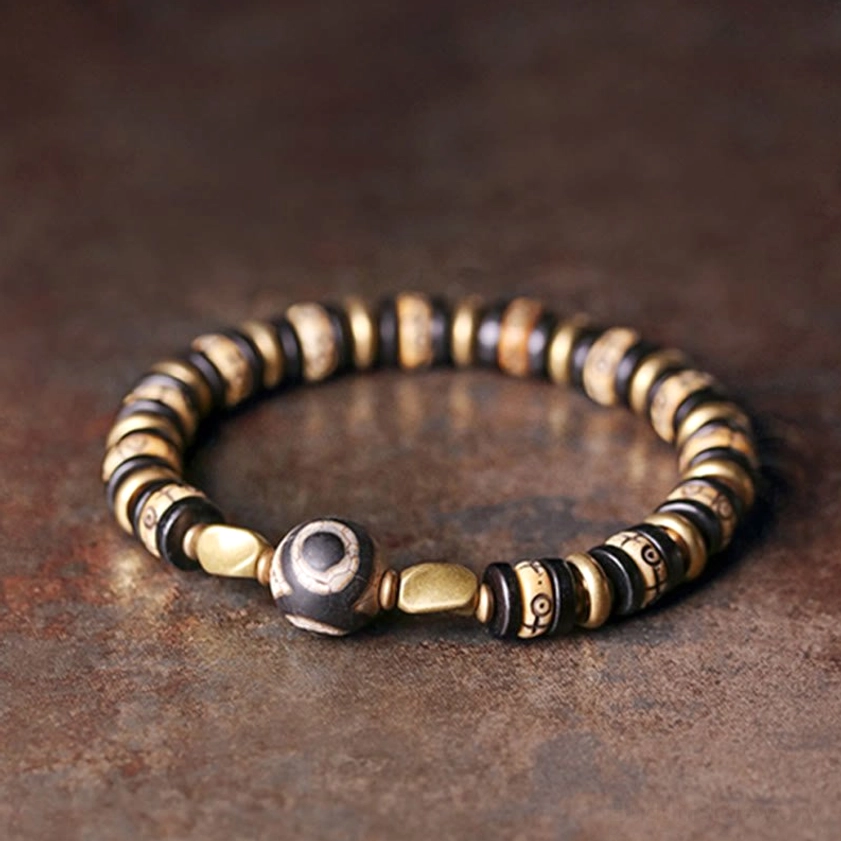 Tibetan Buddhist bone beads bracelet on dark metal backdrop showing warm brown and bronze tones with evenly arranged design