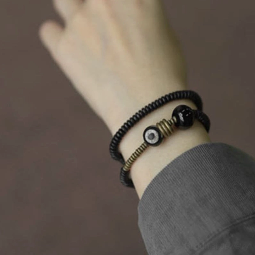 Ebony wood double wrap bracelet worn on wrist with gray sleeve cuff indoor setting