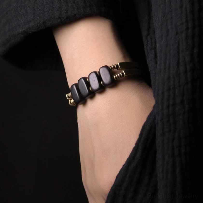 Stacked square ebony wood beads with brass metal connectors on Buddhist protection bracelet