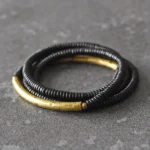 Ebony wood brass copper multilayered Buddhist bracelet with curved brass accents on dark tabletop