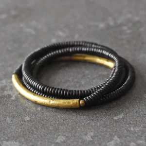 Ebony wood brass copper multilayered Buddhist bracelet with curved brass accents on dark tabletop