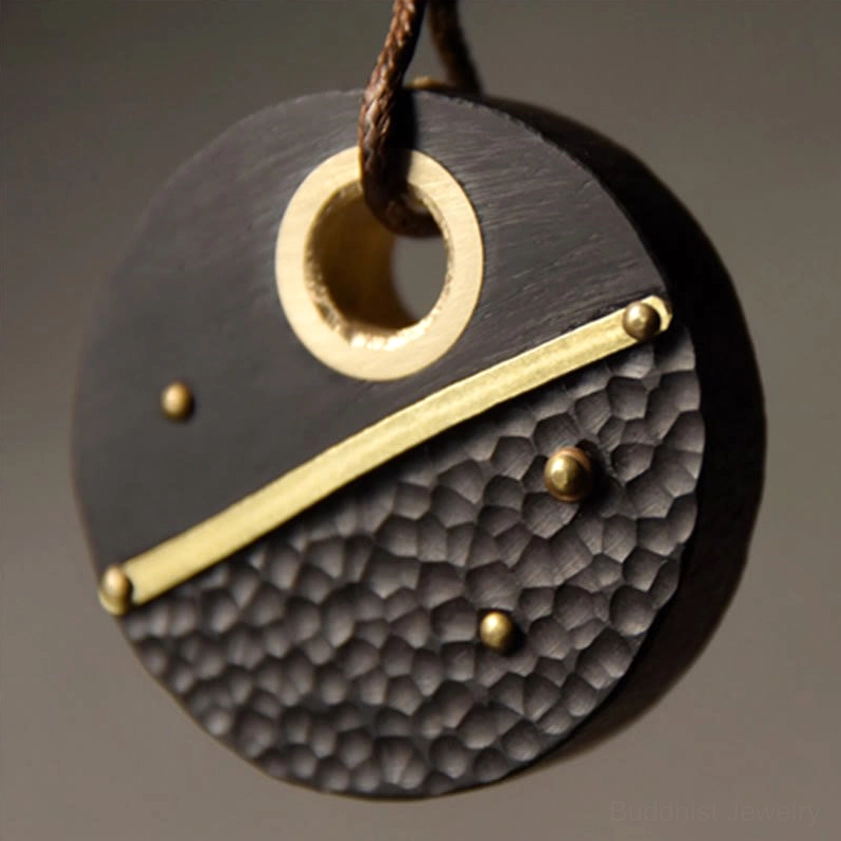 Close-up front view of ebony wood Buddhist peace pendant necklace, highlighting hammer texture, brass inlay, and brass hanging ring