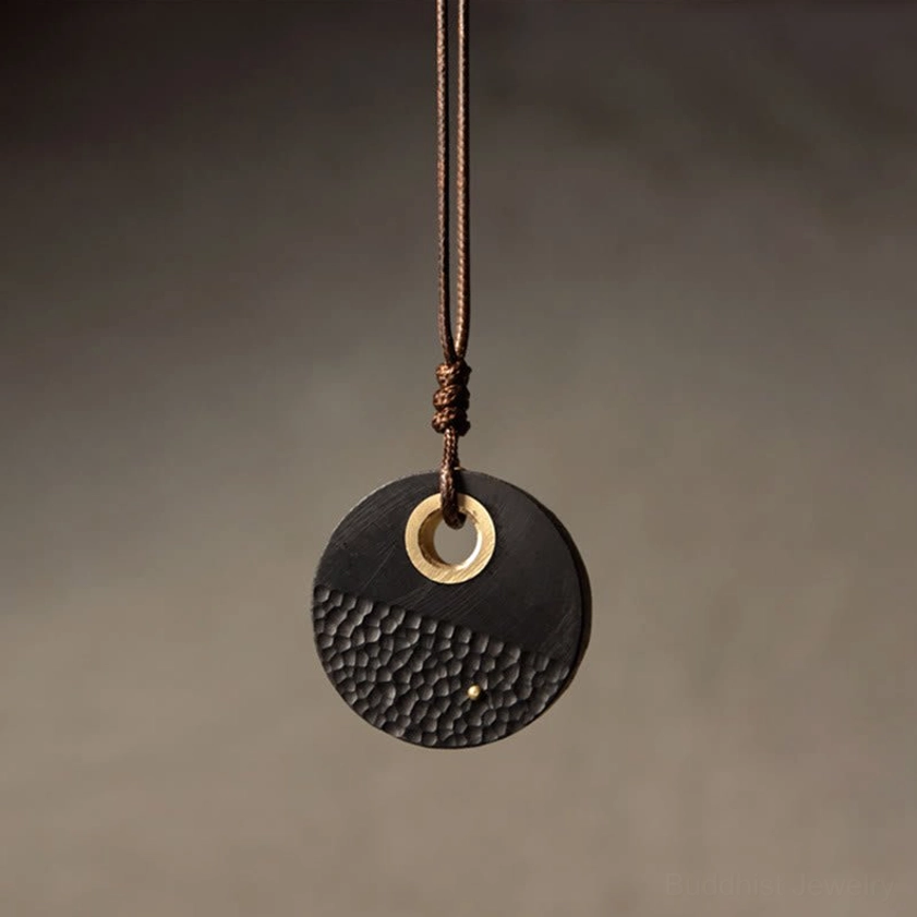 Mini compact ebony wood Buddhist peace pendant with hammered rear texture and natural wax rope, hanging front view