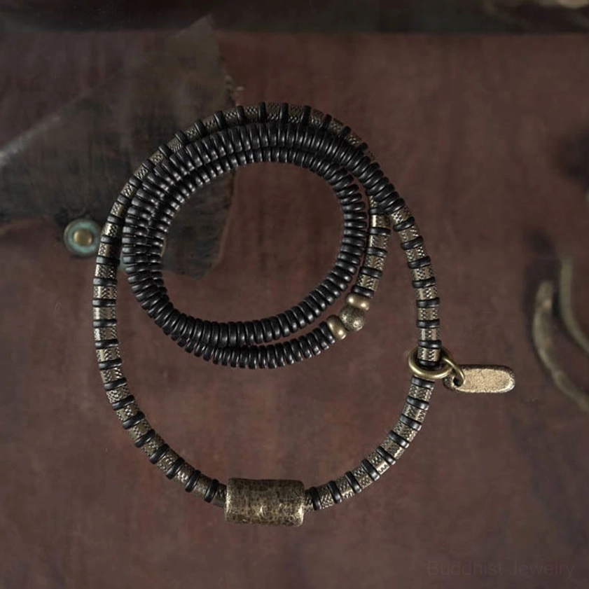 Multilayered black ebony wood Buddhist bracelet flat lay showing multiple coiled strands with copper barrel beads