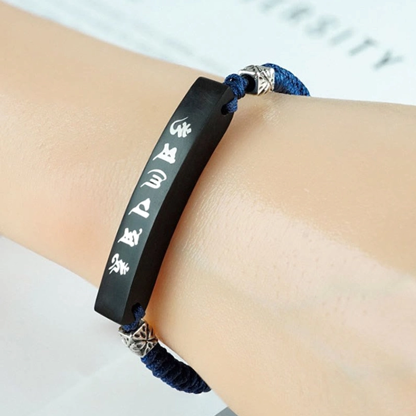 Ebony wood Om Mani Padme Hum bracelet worn on human wrist showing clear view of white engraved mantra on silver-inlaid ebony plate with adjustable navy cord