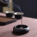 Ebony wood Buddhist incense burner with brass insert, burning incense with smoke on bamboo tea mat