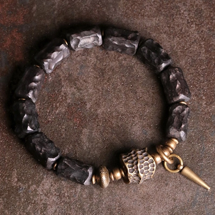 Ebony wood copper couple bracelet flat lay featuring dark beads with antique bronze spike pendant and metal accents for protection and balance