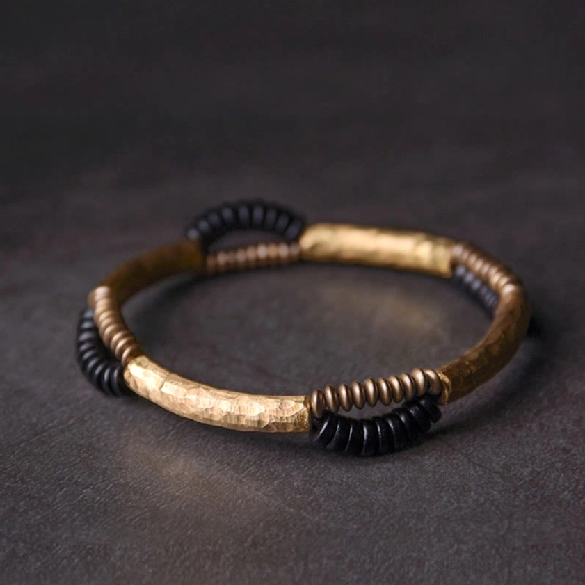 Handmade ebony wood and copper Buddhist bracelet flat lay top-down view showing hammered copper segments and mixed black wooden spacer beads