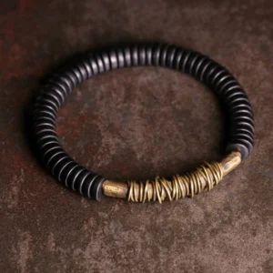 Ebony wood copper Buddhist bracelet overhead flat lay view showing black wooden disc beads with polished brass wrapped accent, perfect for meditation and spiritual grounding