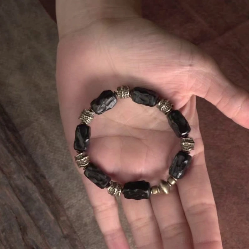 Buddhist bracelet with ebony wood and copper beads displayed on palm
