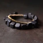 Ebony wood and copper double wrap bracelet with bronze metal accents displayed on dark surface from three-quarter angle view