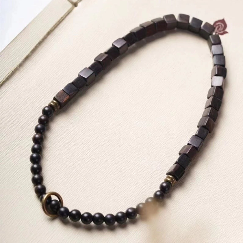 Double wrap ebony wood bracelet showing alternating bead pattern with metal ring clasp on light paper background