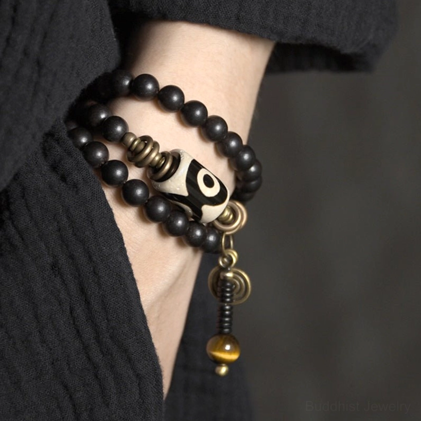 Close-up side view of ebony wood dzi bead bracelet worn on wrist showing natural fit and comfort on black linen