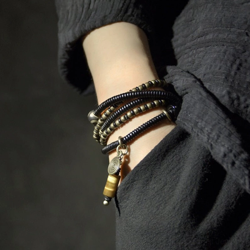 Ebony wood dzi bead bracelet worn on wrist side view showing stackable multi-layer design with tiger eye pendant
