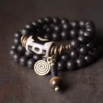 Ebony wood dzi bead copper protection bracelet flat lay on dark rustic surface showing full design with bronze accents