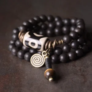 Ebony wood dzi bead copper protection bracelet flat lay on dark rustic surface showing full design with bronze accents