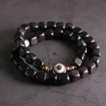 Ebony wood and hand-painted nine-eye dzi bead couple bracelet with copper spacers, top-down flat lay view