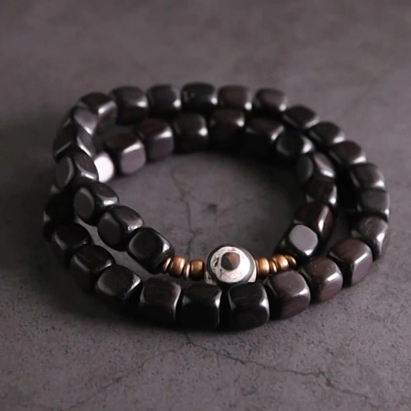 Ebony wood and hand-painted nine-eye dzi bead couple bracelet with copper spacers, top-down flat lay view