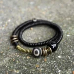 Ebony wood brass dzi bead black onyx double wrap bracelet top view flat lay on gray concrete
