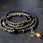 Ebony wood dzi bead copper peace bracelet necklace pendant flat lay overhead view showing multi-layer beaded design with nine-eye dzi bead