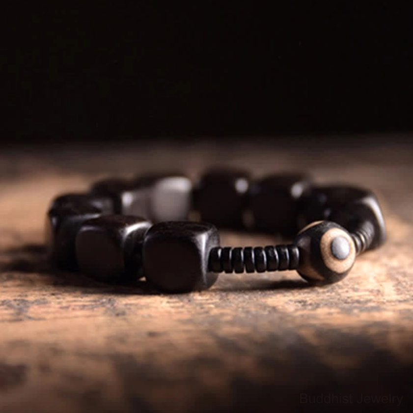 Handmade ebony wood dzi bead bracelet with polished square beads and one-eyed dzi accent, three-quarter view