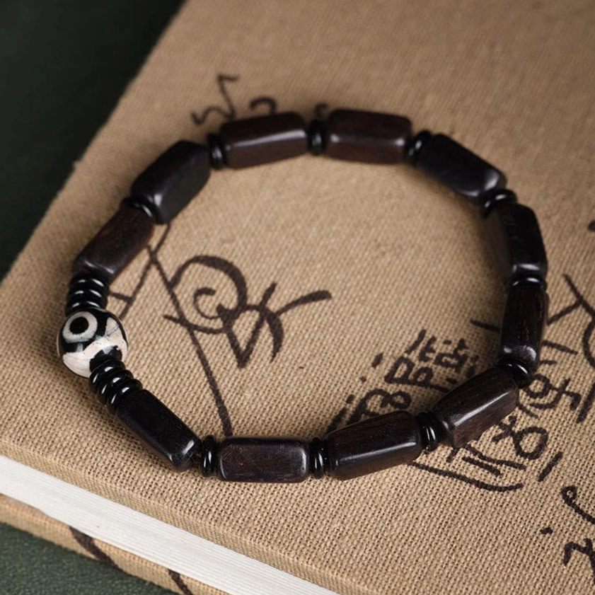 Ebony wood Dzi bead bracelet laid on vintage book flat lay display showing elegant minimalist aesthetic