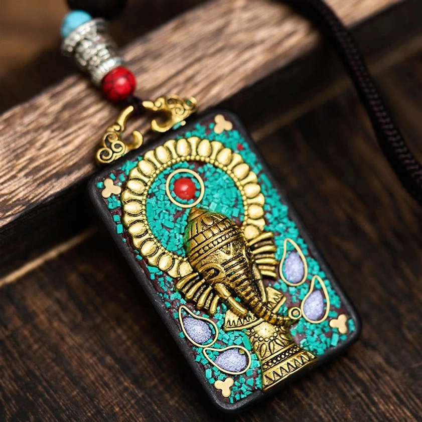 Handcrafted ebony wood Ganesha elephant pendant with turquoise inlay and gold carving on wooden surface