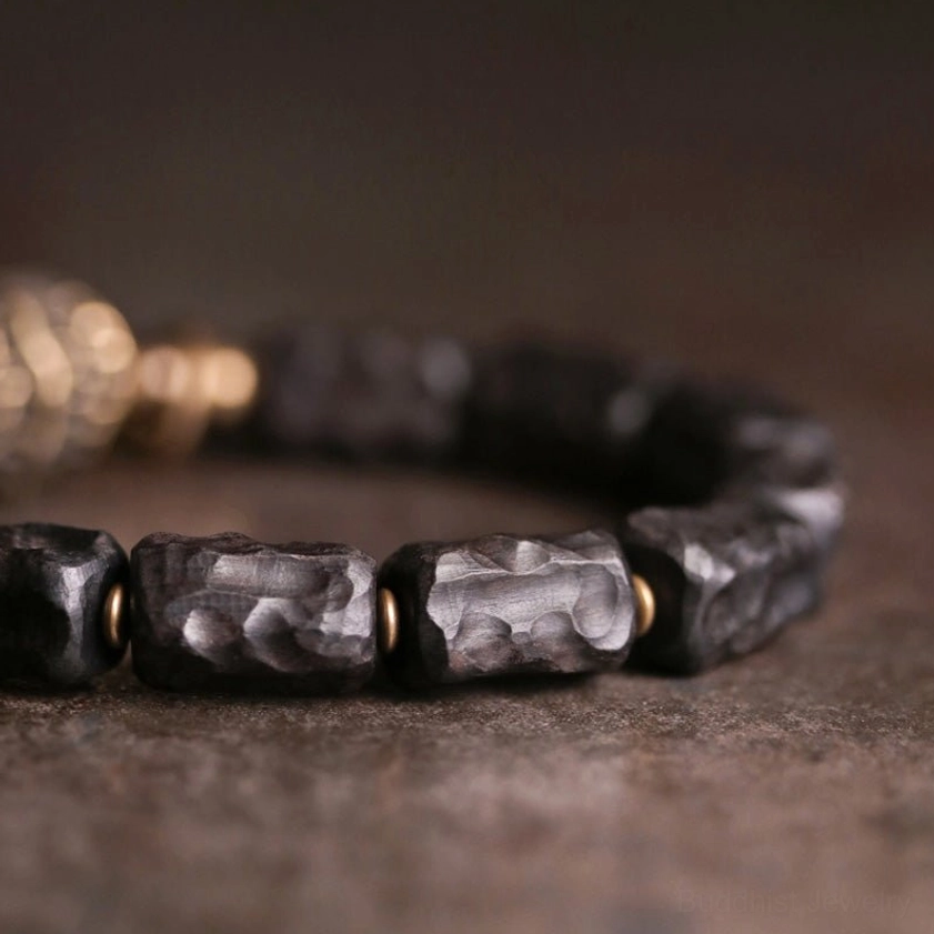 Close-up of ebony wood beads and copper metal rings showing carved wood grain pattern and spiritual bracelet craftsmanship