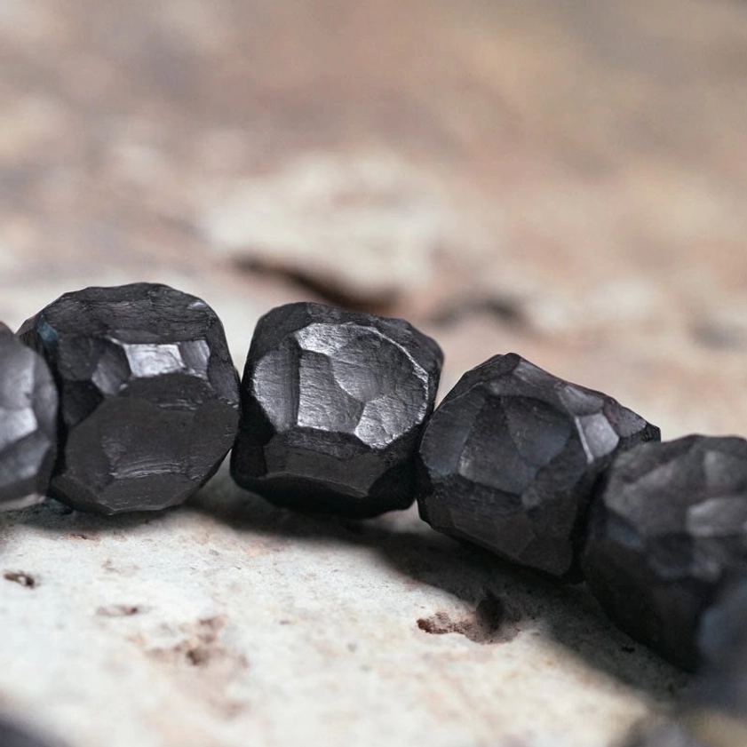 Close-up detail of faceted matte black ebony wood beads on Buddhist mala bracelet