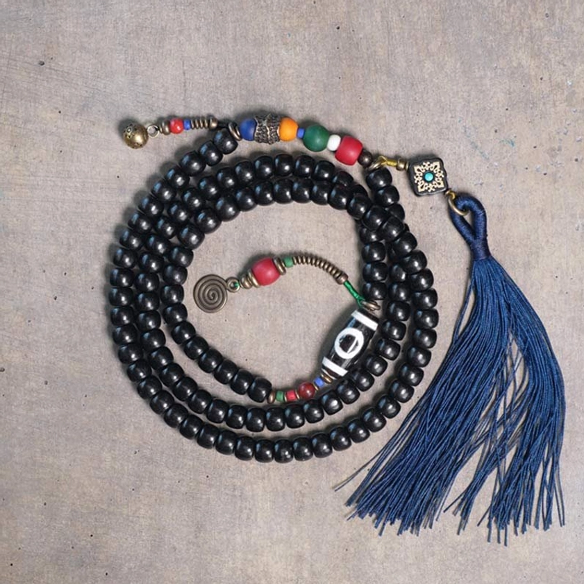 108 bead ebony wood mala bracelet with hand-painted dzi bead and navy blue tassel - flat lay display