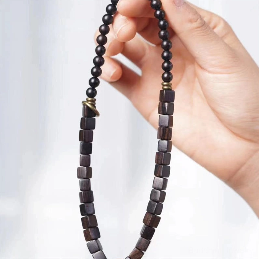 Close-up detail of ebony wood prayer bracelet with alternating square and round beads metal spacers on white background
