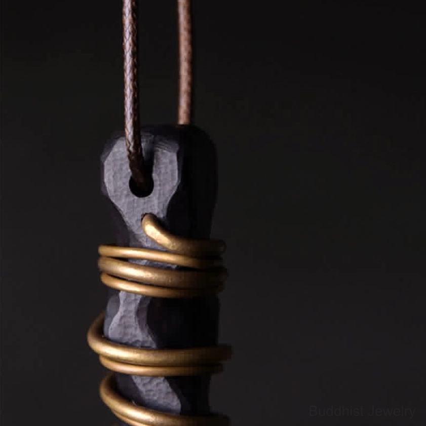 Ebony wood zen pendant top-down macro close-up showing brass wrapping and cord hole detail