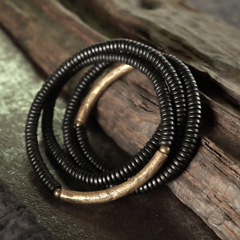 Close-up view of ebony beads and aged brass hardware in layered Buddhist bracelet design