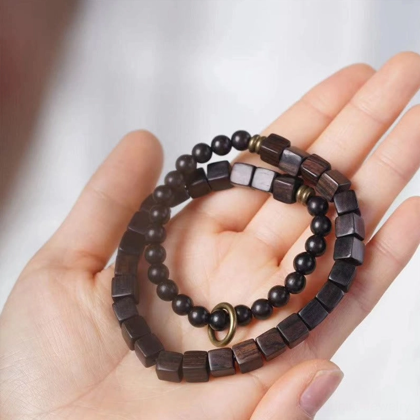 Ebony wood square beads Buddhist meditation bracelet close-up with mixed bead shapes and copper metal fastener on white background