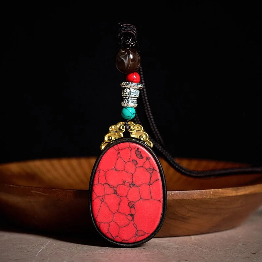 Red cracked stone ebony wood pendant necklace with decorative beaded chain, artisanal Buddhist-inspired design front view
