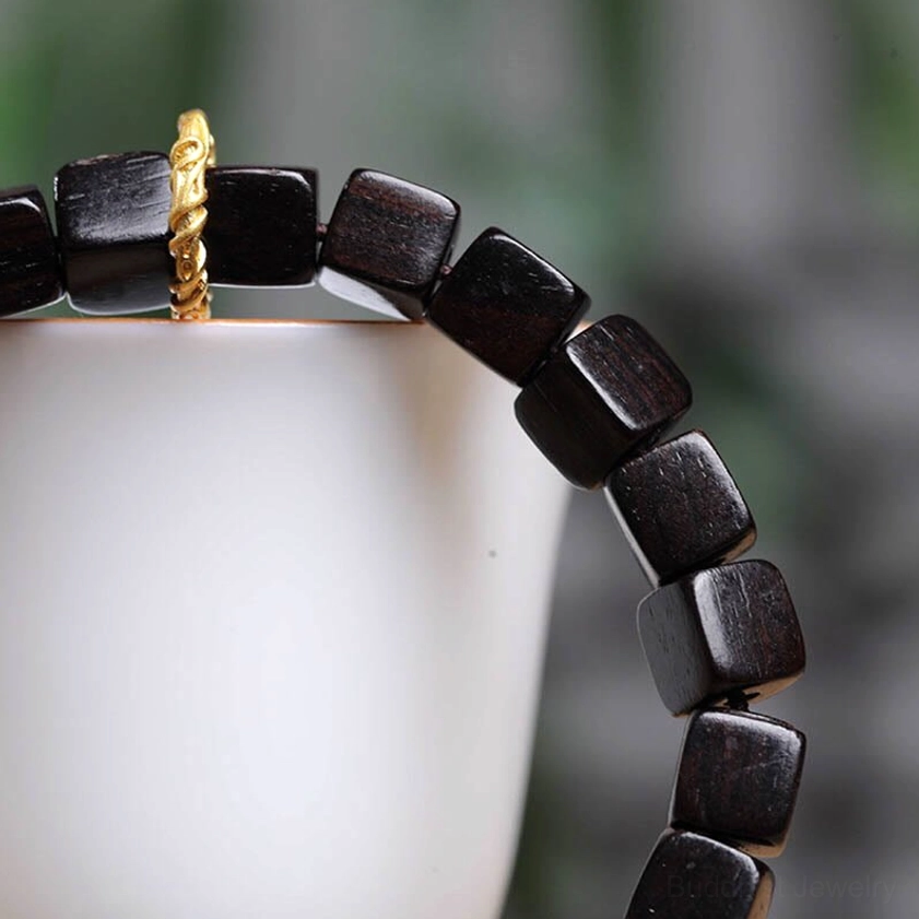 Faceted ebony wood square bead bracelet side close-up showing twisted gold clasp and wood grain detail