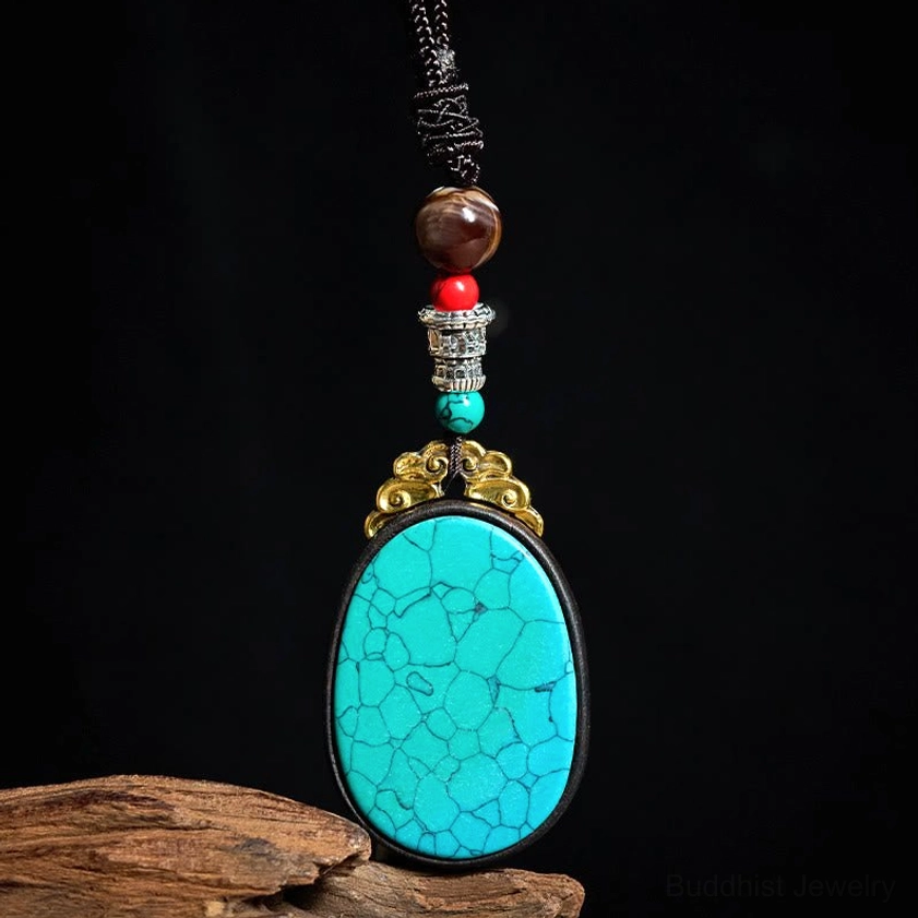 Turquoise cracked stone ebony wood oval pendant with beaded accents on weathered wood backdrop, detail shot