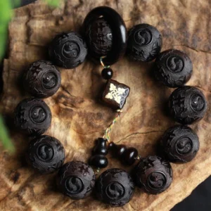 Ebony wood yin yang carved bracelet with 12 beads displayed on wooden bark surface, showing intricate hand-engraved designs and copper ring accent for balance and spiritual harmony