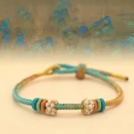 Multicolor eight-thread peace knot braided bracelet with peach blossom charm on Chinese landscape background