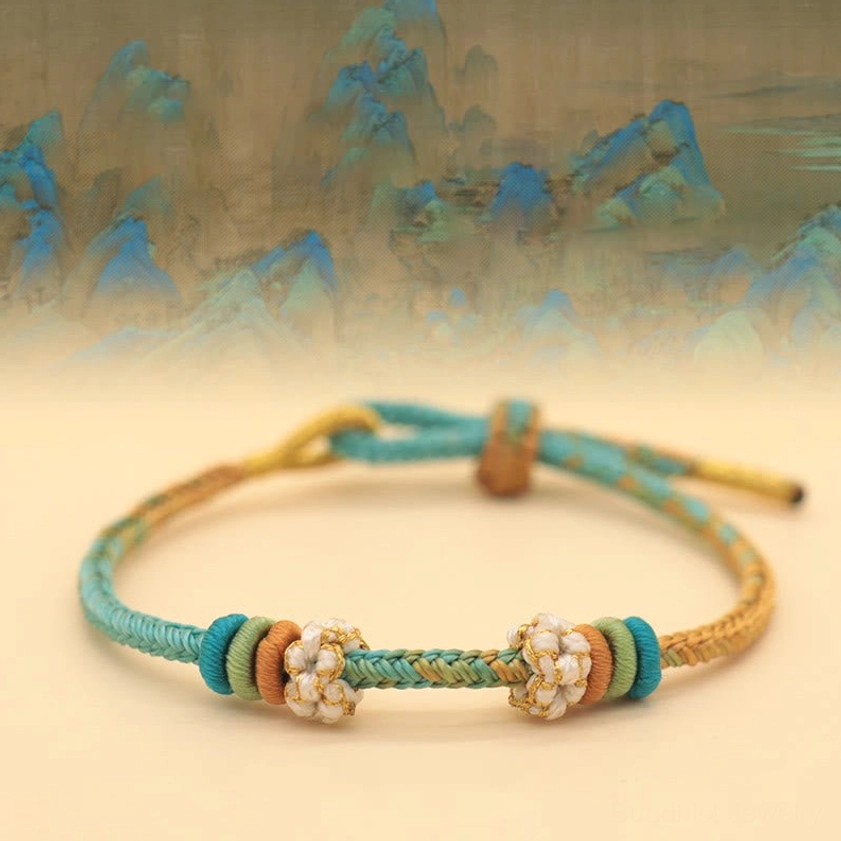 Multicolor eight-thread peace knot braided bracelet with peach blossom charm on Chinese landscape background
